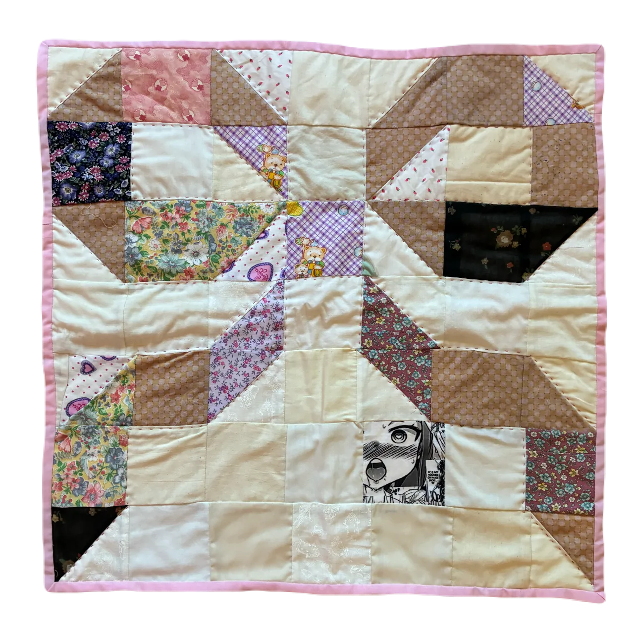 Small square patchwork quilt photographed against a black background, showing a large bow or pinwheel block formed by warm brown, cream, and floral cotton fabrics including purple florals, dark brown, and a small anime-printed patch, with a pink border